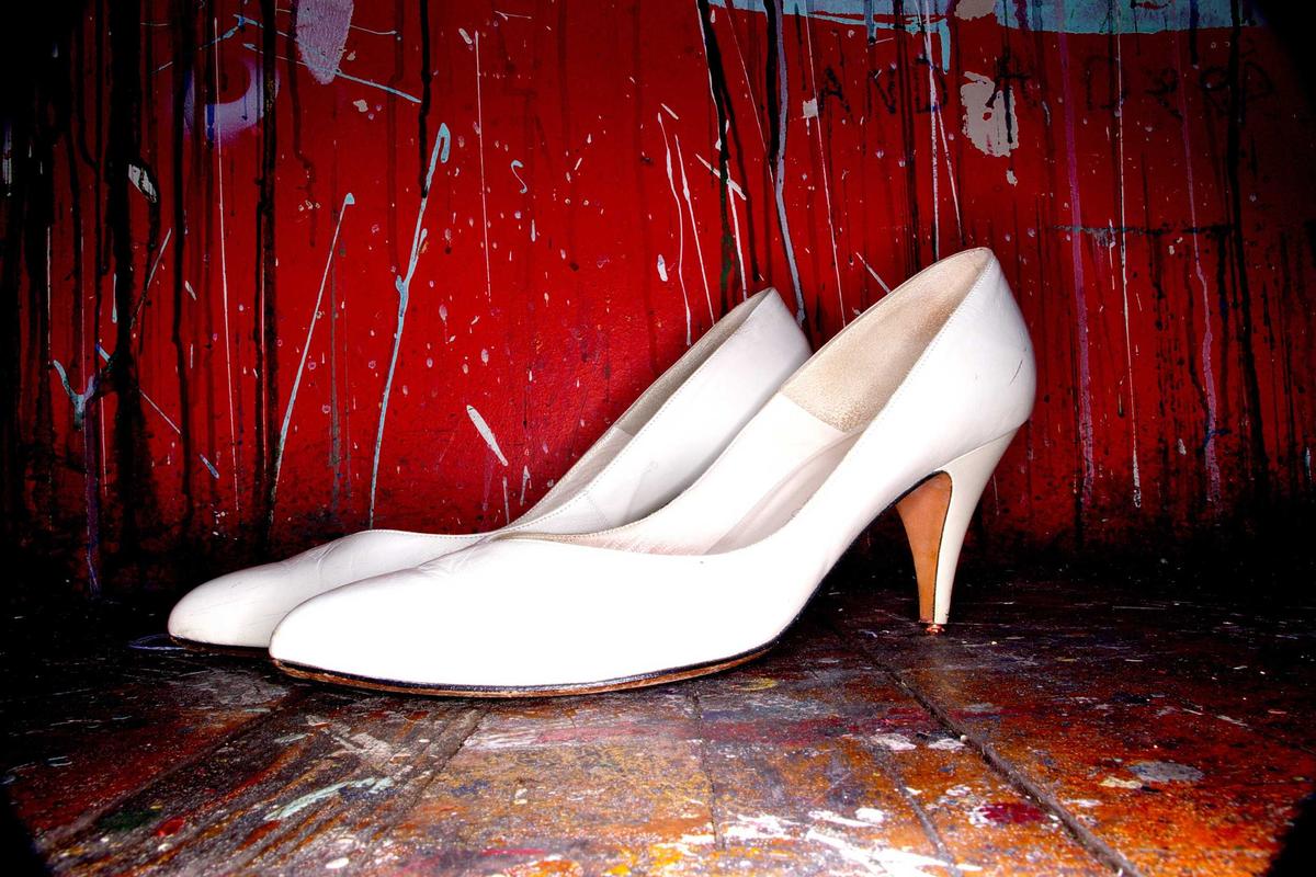 Weiße Brautschuhe vor roter Wand