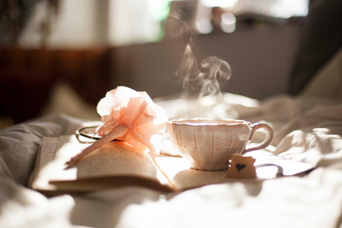 Teetasse und Blüte auf weißer Bettwäsche